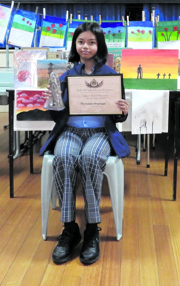 Yzabella Ampogan with her winning entry, Australian Soldier, and library book to the left.