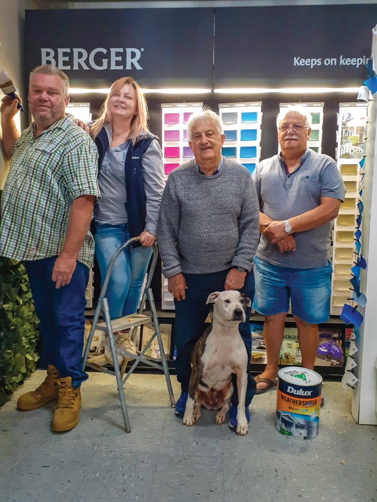 Ivan Kolinac Junior (second from right) with resident dog, Zee, and (left to right) Tony Wheeler, Bronte Kolinac and Brian Kolinac at the family paint store. Photo credit: Nardia Keenan