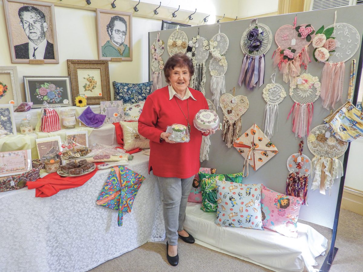 Judy Farquharson surrounded by crafts and cakes at the Trades Hall stall. Photo credit: Nardia Keenan